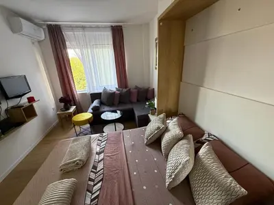 a bedroom with a large bed and a living room at Moderan Studio na Trgu Republike - Centar in Podgorica