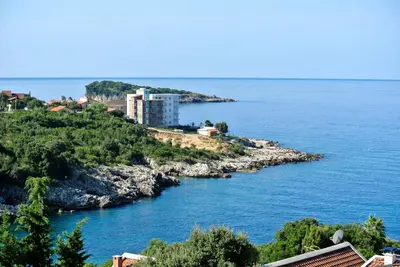 a building on a hill next to a body of water at Apartments Klara in Utjeha