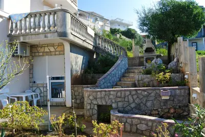 a house with a staircase and a stone wall at Apartments Klara in Utjeha