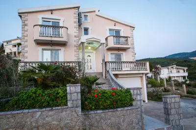 a large pink house with balconies and flowers at Apartments Klara in Utjeha