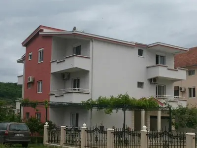 a white and red building behind a fence at Apartments Ela in Ulcinj