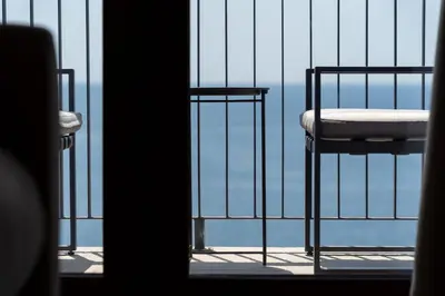a chair on a balcony with a view of the ocean at Niki Apartments Pržno in Sveti Stefan