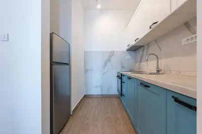 a kitchen with blue cabinets and a stainless steel refrigerator at Niki Apartments Pržno in Sveti Stefan
