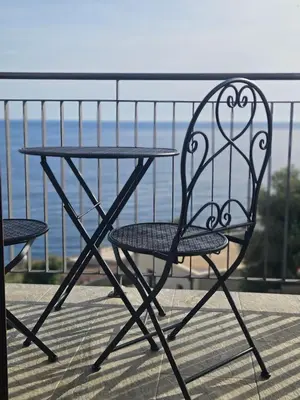 a table and chair on a balcony with a view of the water at Niki Apartments Pržno in Sveti Stefan