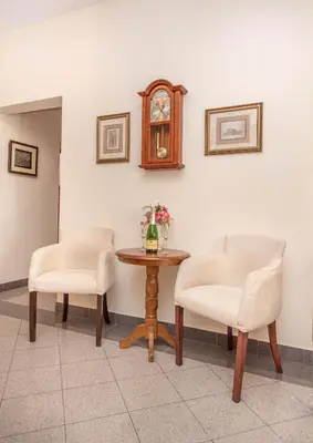 two chairs and a table with a clock on the wall at S&P City Center Apartments in Kotor