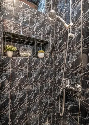 a bathroom with a shower with a black marble wall at S&P City Center Apartments in Kotor