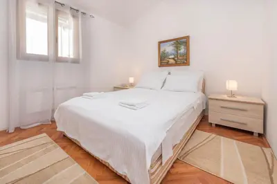 a white bedroom with a large bed and a window at S&P City Center Apartments in Kotor