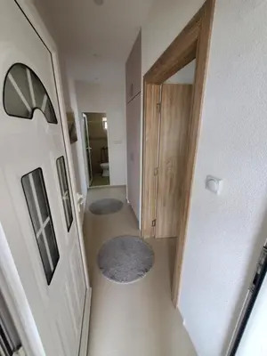 a hallway with a door and two rugs on the floor at Apartmani Liki in Ulcinj