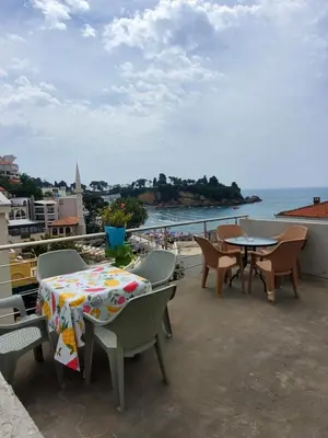 a patio with tables and chairs and a view of the ocean at Apartmani Liki in Ulcinj