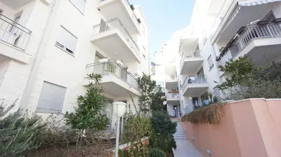 an apartment building with balconies and trees on a street at Petrovac Bay Apartments in Petrovac na Moru