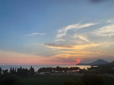 a sunset over the ocean with trees and the sky at Ačanski Apartments Bar in Bar