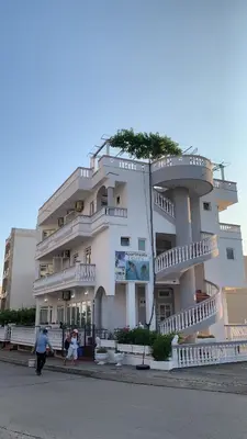 a large white building with people walking in front of it at Apartments Delfin in Ulcinj