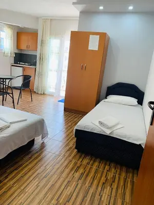 a room with two beds and a cabinet and a table at Apartments Delfin in Ulcinj