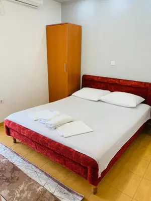 a bedroom with a large bed with a red headboard at Apartments Delfin in Ulcinj