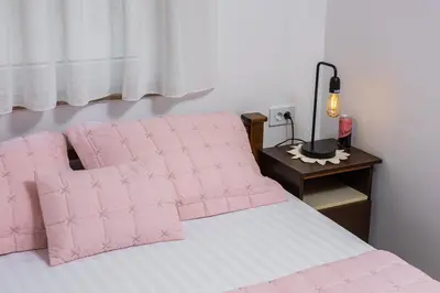 a bed with pink pillows and a table with a lamp at Adzic Apartments in Budva