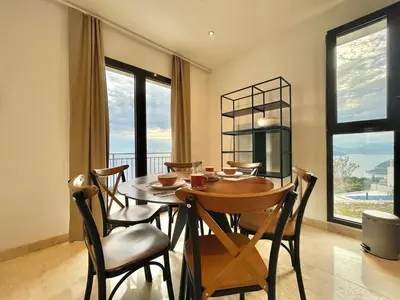 a dining room with a table and chairs and windows at Family Vacation Villa Rezevici in Budva