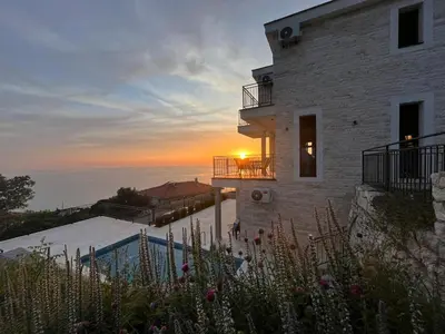 a house with the sunset in the background at Family Vacation Villa Rezevici in Budva