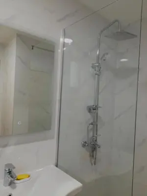 a white bathroom with a shower and a sink at Lux studio apartment Bečići-Budva in Budva