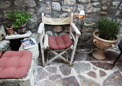 a chair sitting next to a stone wall with a table at Best Location Old Town Budva Rooms in Budva