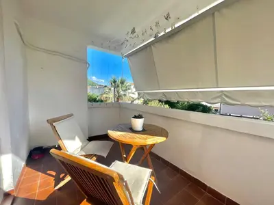 a small balcony with a table and chairs and a window at Family One bedroom apartment with Garden view in Budva
