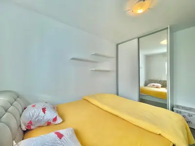 a bedroom with a yellow bed and a mirror at Family One bedroom apartment with Garden view in Budva