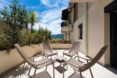 a row of chairs and a table on a balcony at Bonita Residence in Dobrota