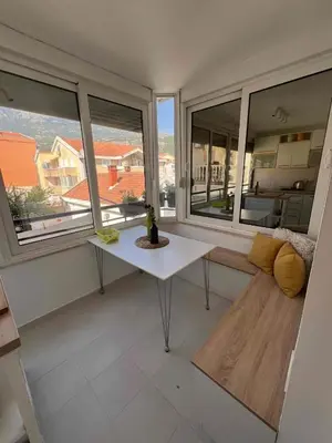 a living room with a table and two windows at Lamada One Bedroom Apartment in Budva