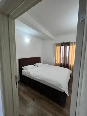 a bedroom with a bed with white sheets at Cezar Apartment 3 in Podgorica
