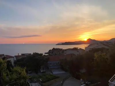 a sunset over a city with the ocean and a city at Apartment Skada in Sveti Stefan