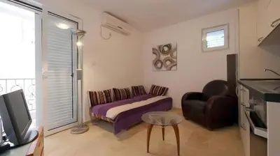 a bedroom with a bed and a couch and a tv at Apartment Skada in Sveti Stefan