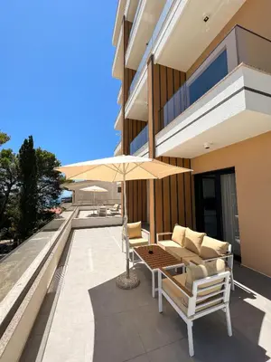 a patio with a table and chairs and an umbrella at Square Residence & Pool in Ulcinj