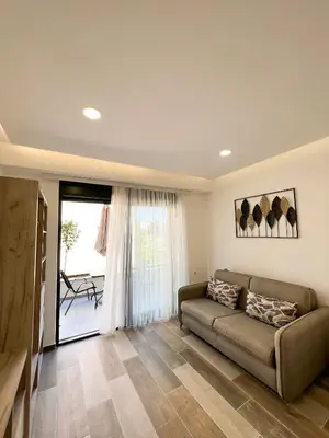 a living room with a couch and a large window at Square Residence & Pool in Ulcinj
