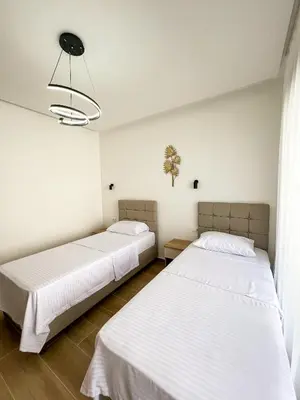 two beds in a room with white walls at Square Residence & Pool in Ulcinj