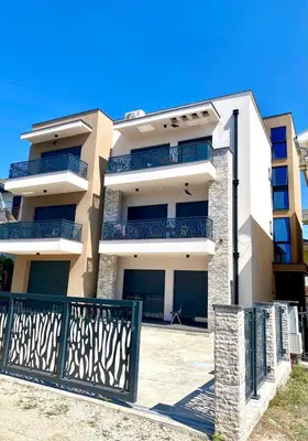 a white building with blue balconies and a gate at Miran San in Donji Štoj