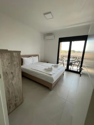 a white bedroom with a bed and a balcony at Miran San in Donji Štoj