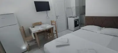 a small room with a bed and a table and a kitchen at Apartmani Murić Bar in Bar