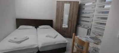 a bedroom with two beds and a chair and a window at Apartmani Murić Bar in Bar