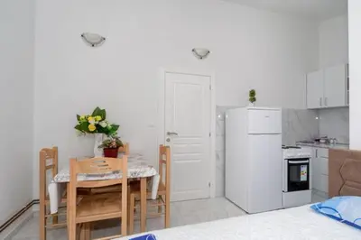 a kitchen with a table and a white refrigerator at Apartmani Murić Bar in Bar