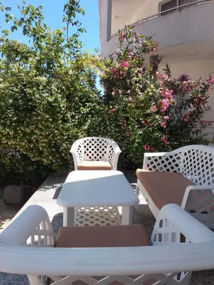 two white chairs and a table on a patio with flowers at Rinia Apartments in Ulcinj