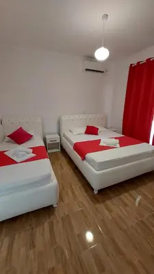 two beds in a room with red curtains at Rinia Apartments in Ulcinj