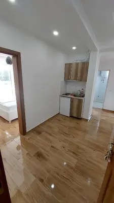 a kitchen with white walls and a wooden floor at Rinia Apartments in Ulcinj