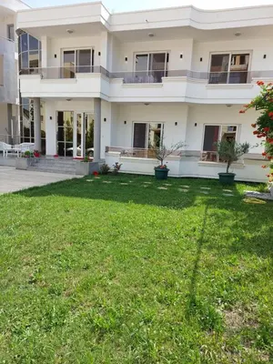 a large white house with a green yard at Rinia Apartments in Ulcinj