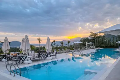 a hotel pool with tables and chairs and a sunset at Montenegro Lodge in Tivat