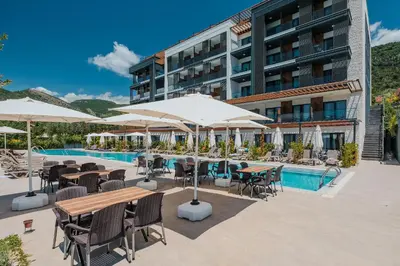 a hotel patio with tables and umbrellas and a pool at Montenegro Lodge in Tivat