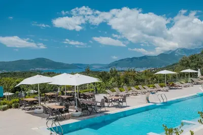 a pool with chairs and tables and umbrellas at Montenegro Lodge in Tivat