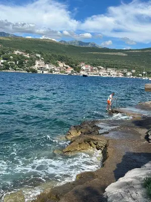 a man standing on the edge of a body of water at Lazarus Bigova apartments in Tivat