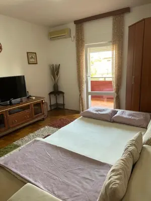 a living room with two beds and a flat screen tv at Bella Apartman in Podgorica