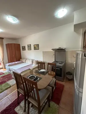 a kitchen and dining room with a table and a bed at Bella Apartman in Podgorica