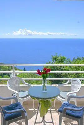 a table with a vase of flowers on a balcony at The rising sun-Stylish Sea View Apartment in Budva