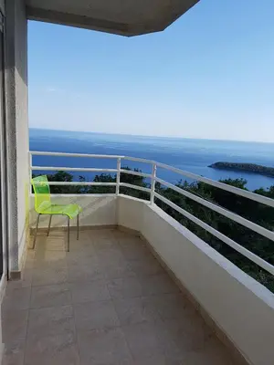 a green chair sitting on a balcony overlooking the ocean at The rising sun-Stylish Sea View Apartment in Budva